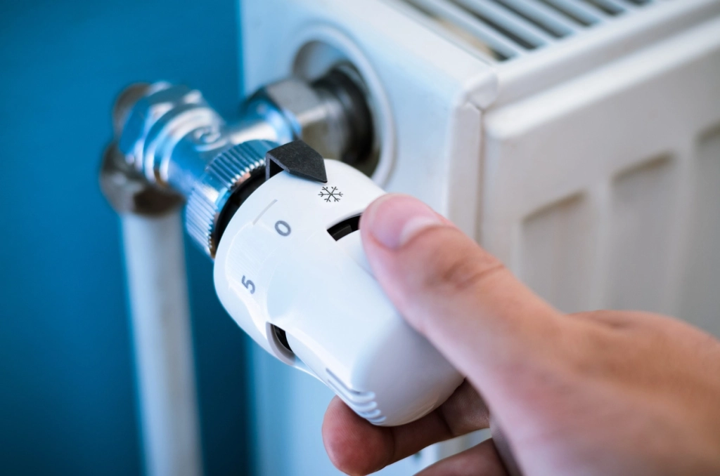 iStock-499804470 One hand adjust thermostat heating valve close up stock photo