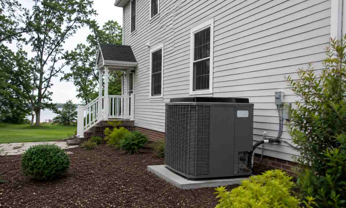 Residential HVAC condensing unit on concrete pad beside a coastal Maryland home, nameplate visible on unit side panel