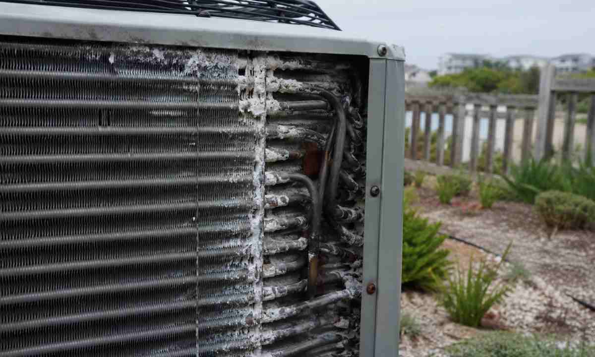 Residential condenser coil fins showing salt air pitting, mineral deposits, and oxidation damage on a coastal Delaware or Maryland property